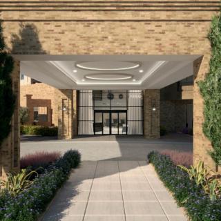 Entrance to a modern building with columns and landscaped walkway.