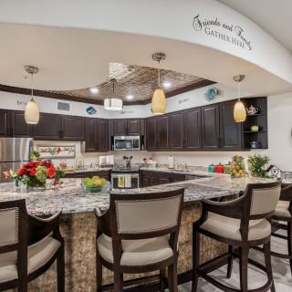A modern kitchen with dark wood cabinets, a stylish countertop, and bar stools arranged for dining.