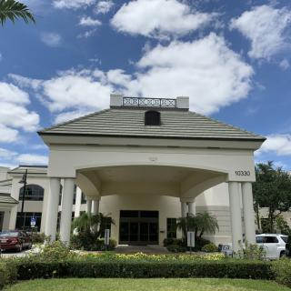 A large building entrance with columns under a partly cloudy sky.