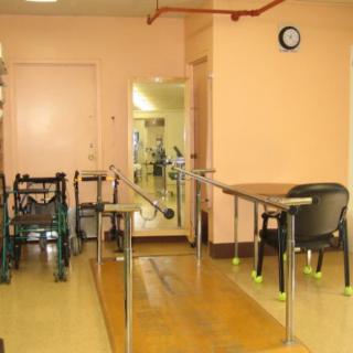 A rehabilitation room with parallel bars and exercise equipment for physical therapy.