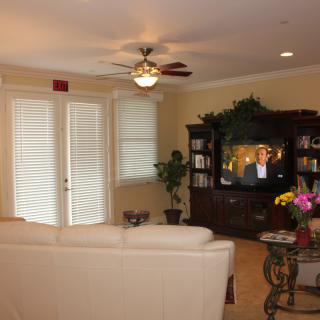 A cozy living room featuring a white sofa, television, ceiling fan, and elegant home decor.