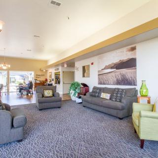 A cozy living room with sofas, carpet, and artwork on the wall.