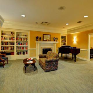 A cozy living room with a fireplace, bookshelves filled with books, a piano, and comfortable seating.