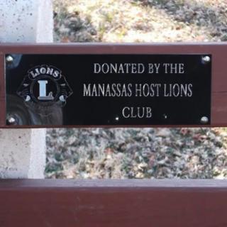 A plaque on a bench indicating it was donated by the Manassas Host Lions Club.