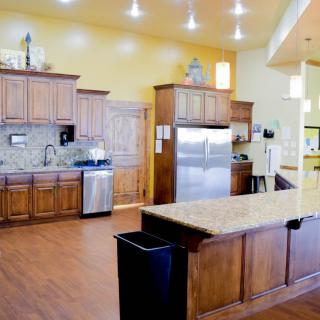 A modern kitchen with wooden cabinets, stainless steel appliances, and a granite countertop island.