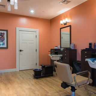 A cozy salon interior with an orange color scheme, featuring a hairdressing chair and mirror.
