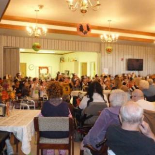 A large group of people seated indoors for a community event.