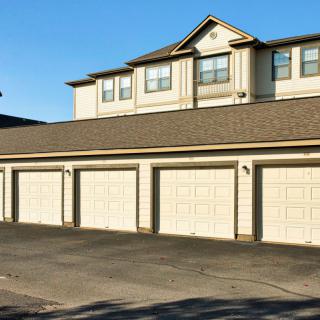 A row of garages beneath a residential townhouse complex on a sunny day.