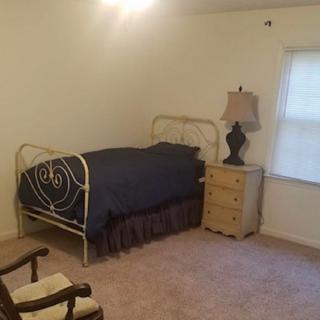 A minimalist bedroom with a single bed, nightstand, and lamp.
