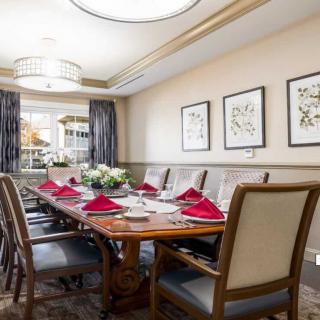A well-decorated dining room with a large table set for dinner, featuring red napkins and floral centerpieces.