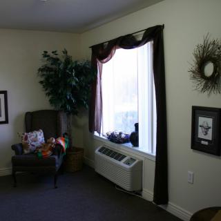 A cozy living room corner with a chair, window, and decorative elements.