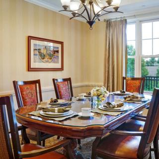 A well-decorated dining room featuring a wooden table set with plates and utensils, surrounded by chairs under an elegant chandelier.