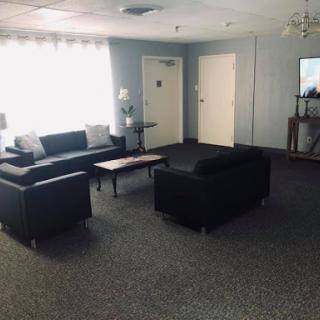 A cozy lounge area featuring black sofas and a coffee table, illuminated by natural light.
