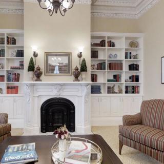 Elegant living room with a central fireplace, surrounded by built-in bookshelves and cozy armchairs.