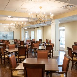 An elegant dining room with multiple tables and chairs, adorned with chandeliers.