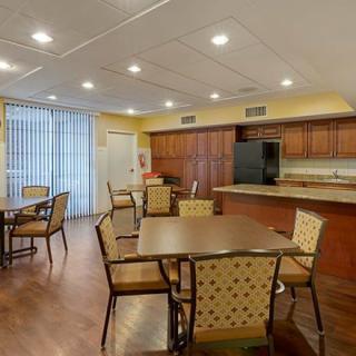 A spacious kitchen and dining area with wooden cabinetry, several tables, and chairs.