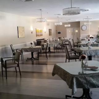 An empty dining room with arranged tables and chairs, featuring modern lighting fixtures and wall decor.