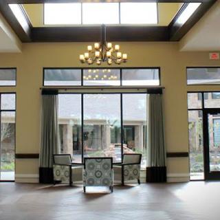 A spacious lobby with large windows, a chandelier, and comfortable seating.