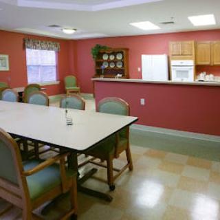 A cozy dining and kitchen area with a large table and chairs, set against warm red walls.