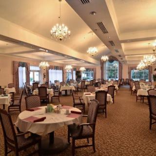 An elegant dining room with chandeliers and neatly arranged tables and chairs.