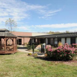 A small building with a gazebo and well-maintained garden area under a clear blue sky.