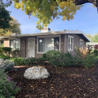 A charming residential house surrounded by a garden with trees and rocks.