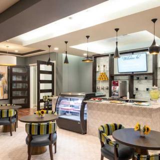 A modern cafe interior featuring a stylish seating area and a sleek counter with a display case.