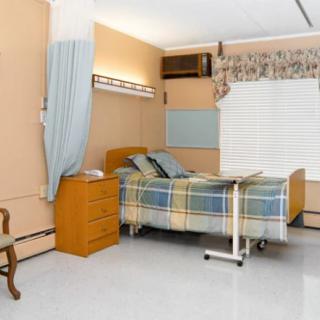 A hospital room with a single bed, curtain, and window.