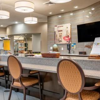 A modern lobby area featuring comfortable seating, a counter with chairs, stylish lighting, and a television.