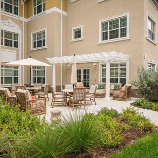 A patio area with outdoor furniture and a garden in front of a building.