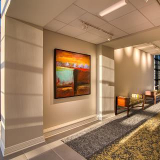 A modern office hallway featuring contemporary artwork and stylish lighting.