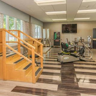 A modern gym space featuring exercise equipment and a set of stairs, designed for fitness and rehabilitation.