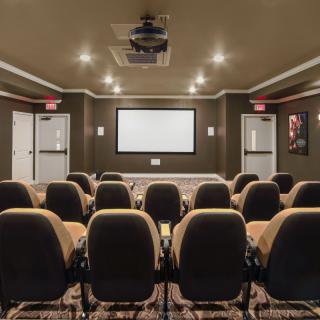 A cozy home theater setup with rows of seating facing a large projection screen.