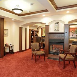 A cozy lounge area with carpeted flooring, comfortable chairs, and a fireplace.