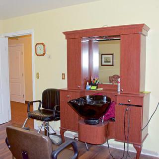 Interior of a hair salon with chairs, a mirror, and a sink for washing hair.