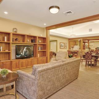 A cozy living room with a large sofa, built-in wooden bookshelves, and a television.
