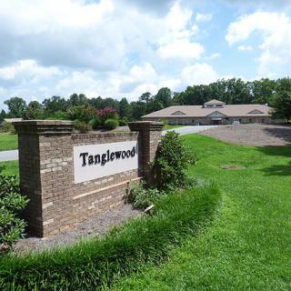 Entrance sign to Tanglewood with a building in the background and a lush green landscape.
