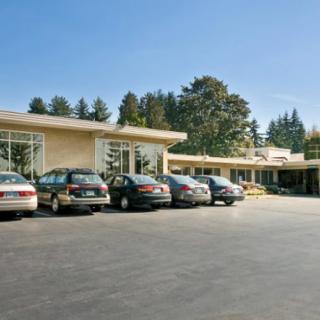 A motel with several parked cars outside on a sunny day.