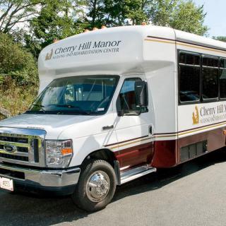A shuttle bus parked outdoors, branded with Cherry Hill Manor.