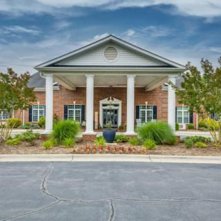 A brick building with a columned entrance and well-maintained landscaping.