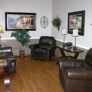 A cozy living room setup featuring comfortable chairs, decorative artwork, and a potted plant.
