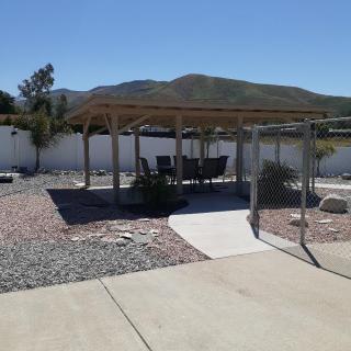 A backyard with a pergola and outdoor seating, set against a mountainous landscape.