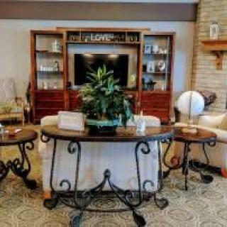 A cozy living room featuring a wooden entertainment center, a coffee table with a plant, and comfortable seating.