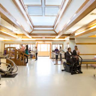 A well-lit rehabilitation center featuring various therapy equipment and patients engaging in physical therapy sessions.