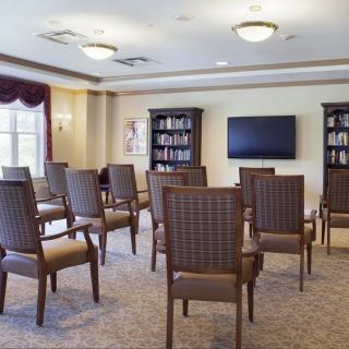 An empty conference room with chairs facing a television and bookshelves.