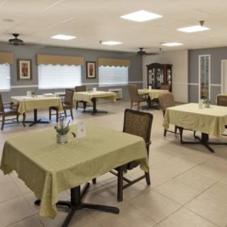 An empty dining room with tables covered in tablecloths and arranged neatly.