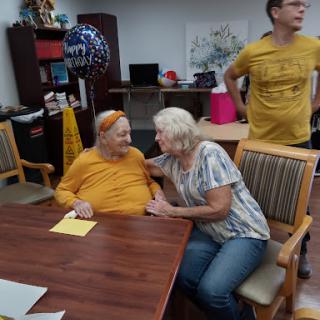 A heartwarming moment of conversation and connection among elderly individuals in a care facility.