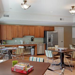 A modern kitchen and dining area featuring wooden cabinets, stainless steel appliances, and tables set with board games.