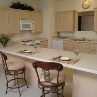 A spacious and modern kitchen featuring light-colored cabinets, a center island with bar stools, and essential appliances.