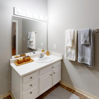 A neatly organized bathroom with a white vanity, mirror, and hanging towels.